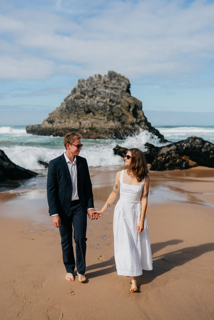 Letní svatební pohoda v Portugalsku: Novomanželé se slunečními brýlemi se smějí u šumícího oceánu